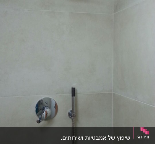 ראש מקלחת עגול וברז חדש על קיר אריחים